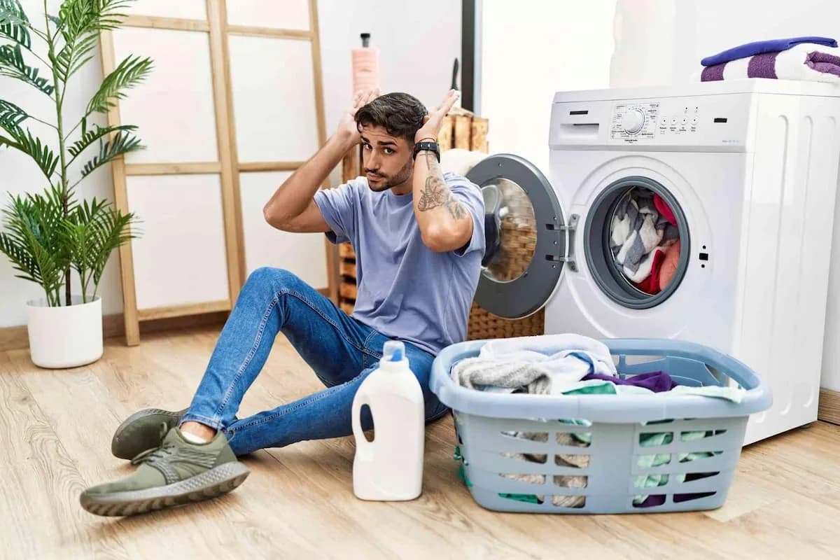 A young man beside a load of laundry, working out the safest way to wash screen-printed tees